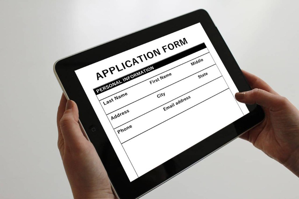 Hands holding a tablet with a digital application form