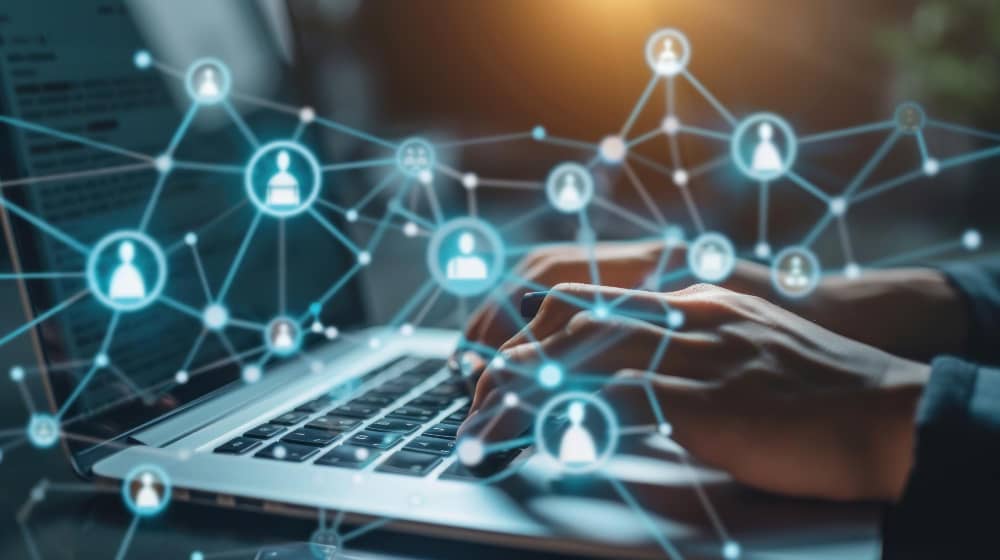 Hands on a laptop with a digital business network overlay